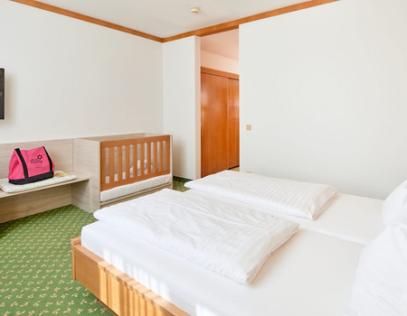 Komfortzimmer mit Gitterbett und Babyausstattung